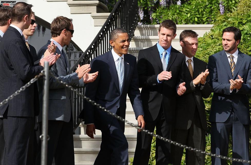 US-Präsident Barack Obama betritt das Rednerpult, die NASCAR-Stars (in Anzug und Krawatte) applaudieren 