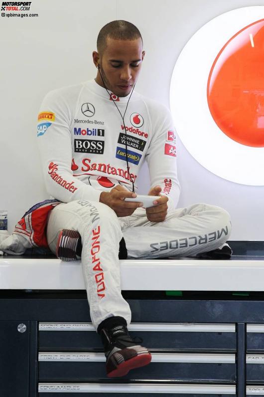 Lewis Hamilton (McLaren) spielt angesichts des Regens mit dem Handy rum