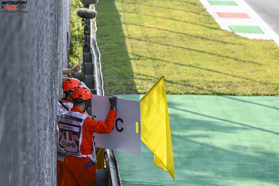 Sportwarte zeigen gelbe Flaggen und das Safety-Car-Schild