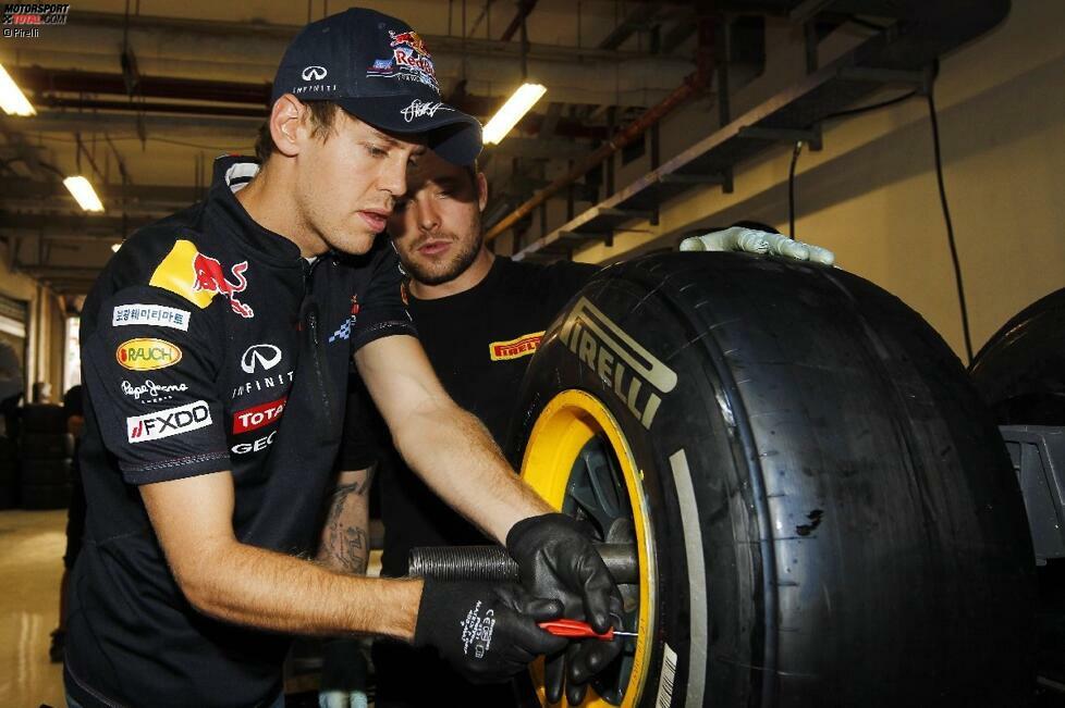 Rennfahren kann er, aber auch Reifen wechseln? Sebastian Vettel lässt sich bei Pirelli erklären, wie man die Reifen von den Felgen zieht und wieder draufpackt.