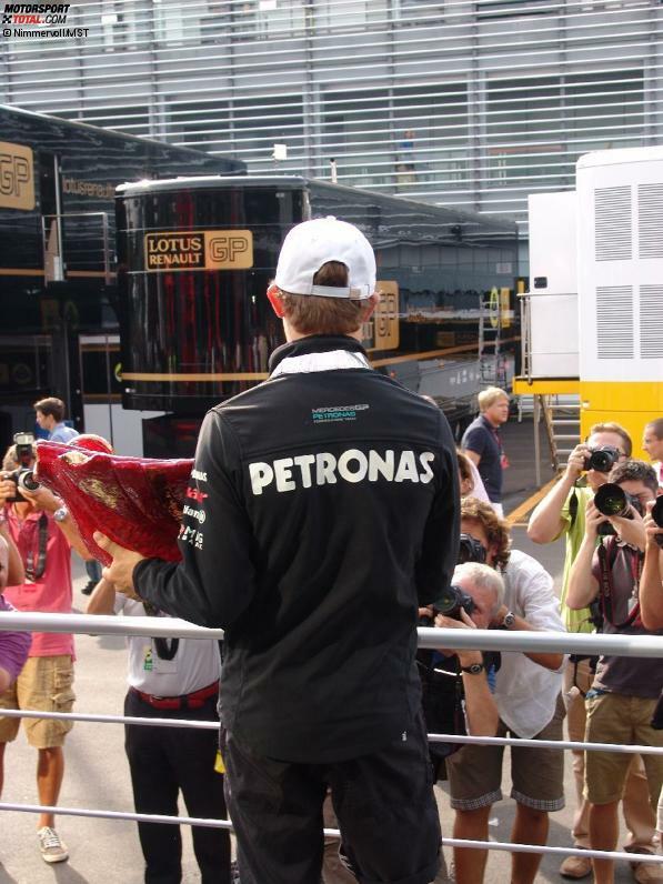 Mehr F1 Backstage geht nicht: Nico Rosberg präsentiert der Fotografen-Meute die Bandini-Trophäe, während wir die Situation von hinten beobachten...
