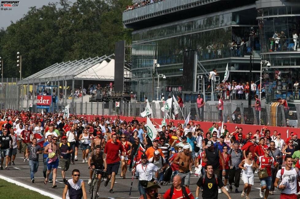 Typisch Monza: Am Ende eines Grand Prix strömen die Fans in richtung Siegerehrung. Kurios ist allerdings der Mann, der den Weg mit dem Fahrrad zurücklegt. Wo hat er den Drahtesel während des Rennens gehabt? Unter seinem Tribünensitz?