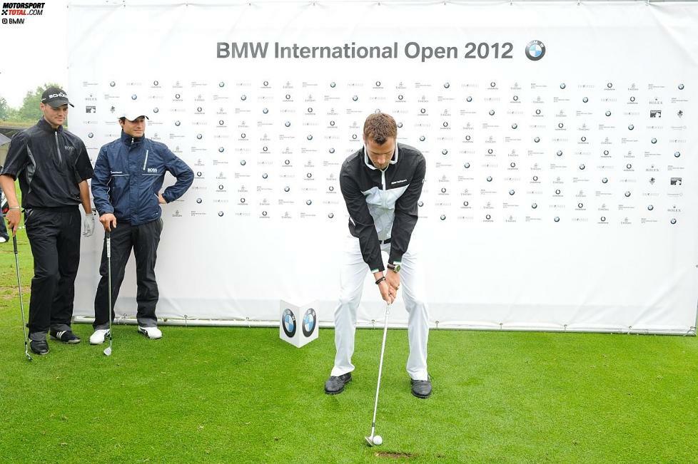 Starker Abschlag: Martin Tomczyk versuchte sich bei den BMW Open in München beim Golf. Profi Martin Kaymer und Bruno Spengler beäugten den Versuch skeptisch.