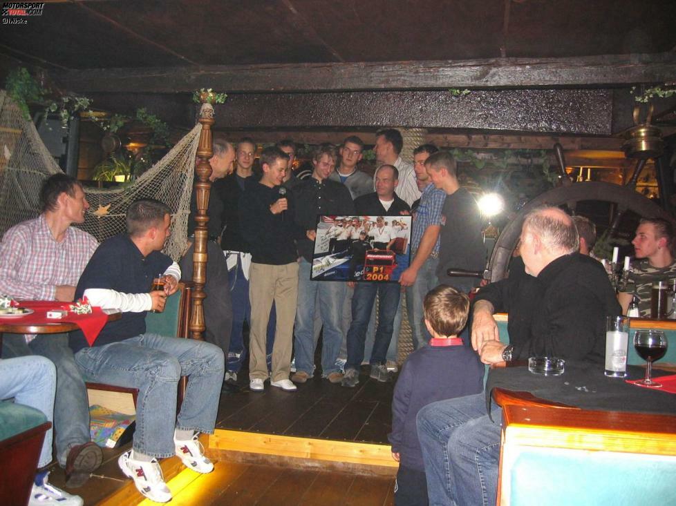 Vettel überreicht das signierte Bild bei der Weihnachtsfeier im Dezember 2004 an seine Crew.