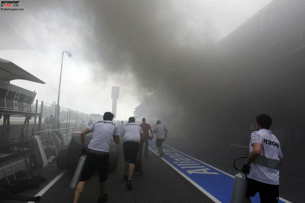 Mercedes-Mechaniker eilen zu Hilfe und halten sich notdürftig ihre eigenen T-Shirts vors Gesicht, um nicht mit einer Rauchgasvergiftung umzukippen.