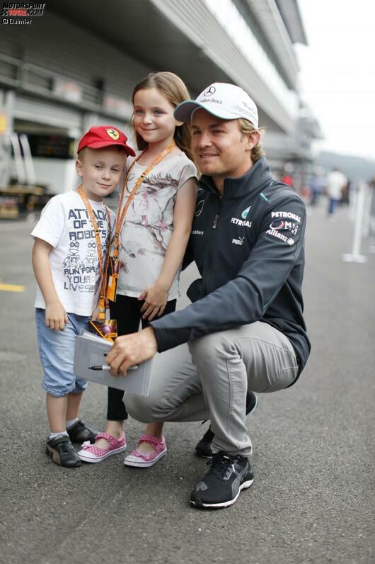 Ein Herz für Kinder: Nico Rosberg mit zwei seiner jüngsten Fans. Bei diesem süßen Kinderlächeln kann man auch mal über die falsche Farbe der Kappe hinwegsehen...