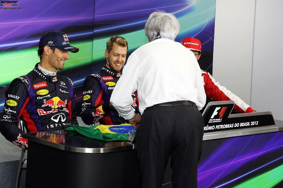 Ganz einfach: Er wollte Webber zum Abschied eine brasilianische Flagge schenken, signiert von ihm selbst und allen Fahrern - aber die Unterschrift von Sebastian Vettel fehlte noch. Also platzte der Formel-1-Boss ins Medien-Kreuzverhör und legte Vettel Flagge und Stift hin.