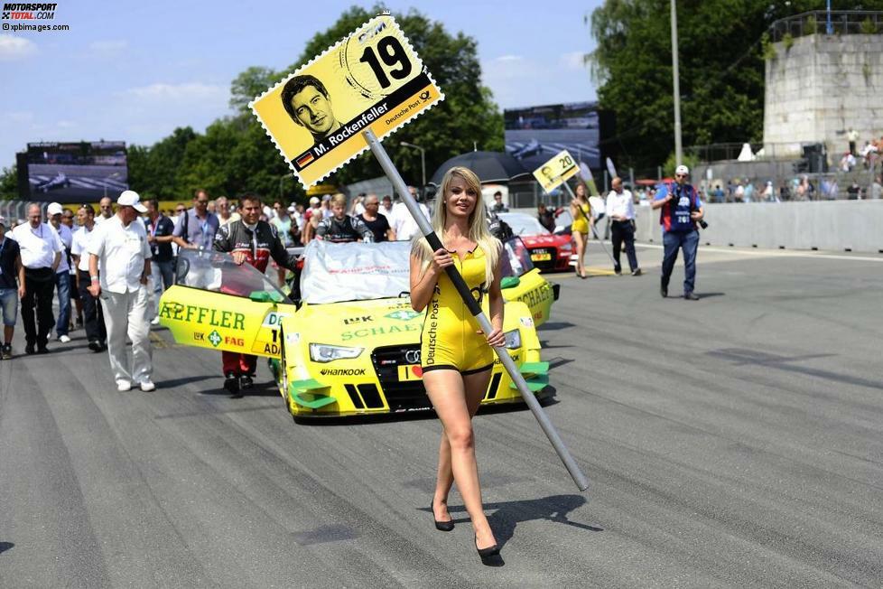 Und einer dieser deutschen DTM-Piloten hat 2013 das große Los gezogen. Die Nummerntafel dieser jungen Dame lässt keinen Zweifel, wessen Fahrzeug hier in die Startaufstellung geschoben wird. Es ist das Auto des neuen DTM-Champions Mike Rockenfeller.