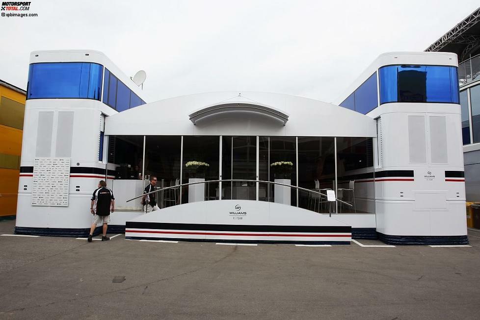 Traditionell und kompakt haust das Williams-Team im Fahrerlager der Formel 1. Dem privaten Rennstall liegt wohl nichts an einer pompösen Präsenz abseits der Strecke. Es ist das Modell Lotus, aber eine Nummer kleiner: Zwei Trucks, dazwischen der Bereich für Fahrer, Teammitglieder und Medien. Ein bisschen 
