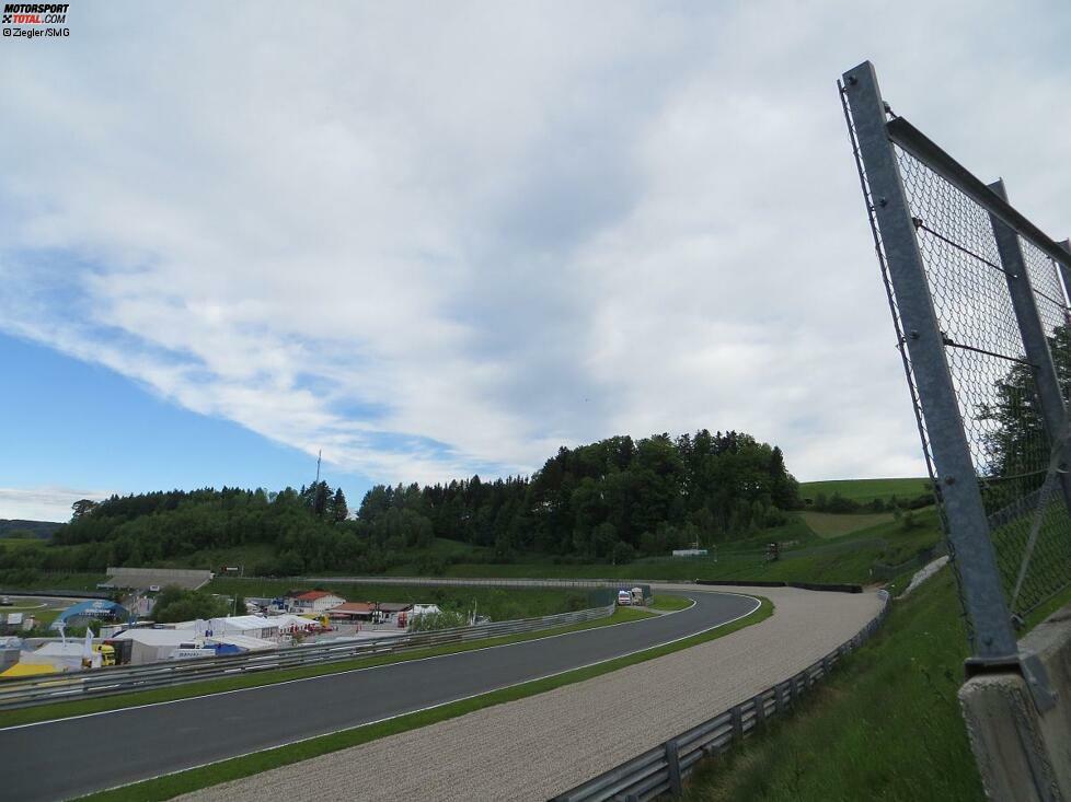 Die Aussicht von unserer Station: Die Einfahrt zur Fahrerlagerkurve, ganz rechts unser FIA-Sicherheitszaun. Dahinter stehen wir während der Sessions, haben den Kurvenein- und Ausgang im Blick. Am linken Streckenrand, bei Nummer 16, steht ein Krankenwagen. Und dort ist auch ein Dixi-Klo. Doch da kannst du nur hin, wenn gerade Pause ist.