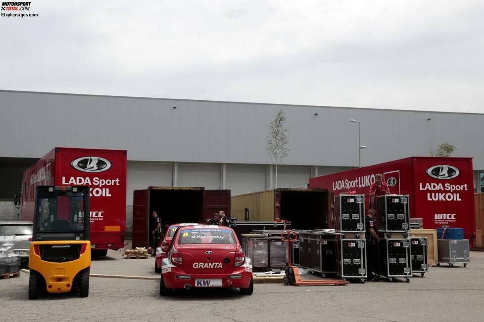 In diesem Bild ist schon zu erahnen, dass es voran geht. Bei Lada warten die zwei Einsatzautos auf die Verladung, direkt daneben die Kisten mit den Ausrüstungsteilen. Die beiden Container sind schon geöffnet und können befüllt werden.