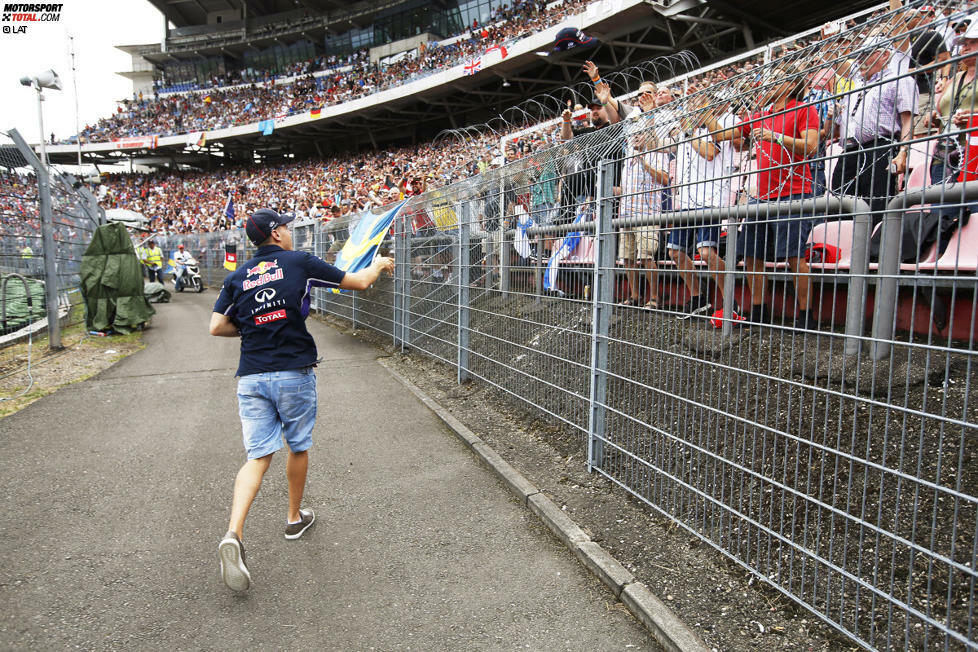 Die, die da sind, sorgen aber für gute Stimmung. Zum Beispiel während der Fahrerparade, als Sebastian Vettel im Motodrom aus seinem Oldtimer springt und signierte Red-Bull-Kappen verteilt.