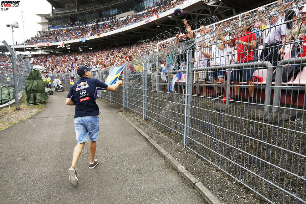 Die, die da sind, sorgen aber für gute Stimmung. Zum Beispiel während der Fahrerparade, als Sebastian Vettel im Motodrom aus seinem Oldtimer springt und signierte Red-Bull-Kappen verteilt.