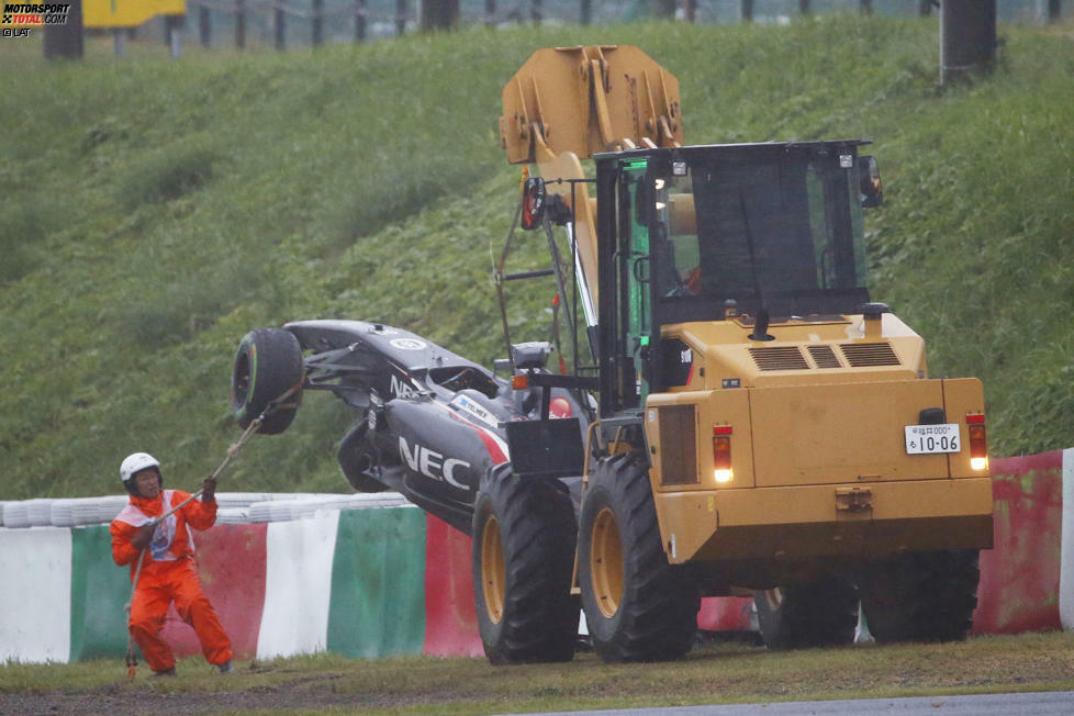 Mit einem gelben Radlader wird der Sauber von der Unfallstelle weggebracht. Ein Streckenposten stabilisiert mit einem Seil das Auto, damit dieses beim Transport nicht pendelt und zusätzlich beschädigt wird.