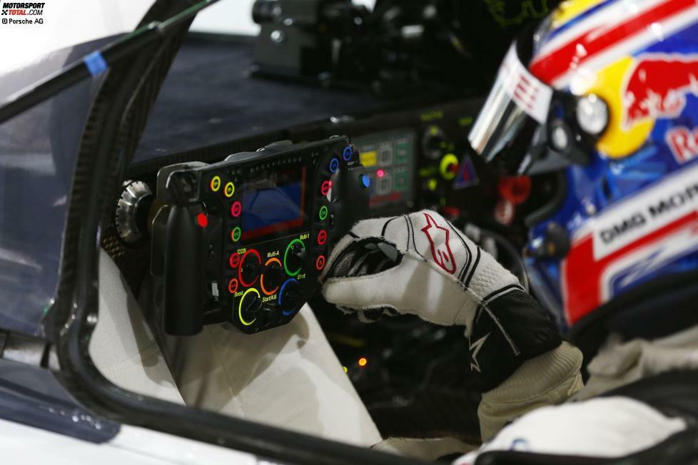 Obwohl es Lenkrad heißt, ist es nicht rund, sondern ein flaches Rechteck. Die Form ist dem Platzbedarf beim Fahrerwechsel geschuldet. Vor allem große Piloten wie Mark Webber (Foto) oder Brendon Hartley hätten sonst Mühe, ihre langen Beine schnell zu verstauen. Im Zentrum befindet sich ein großes Display, das dem Fahrer vielfältige Informationen anzeigt - etwa die Geschwindigkeit, den eingelegten Gang, das aktuell gewählte Motormanagement und den Ladestatus der Lithium-Ionen-Batterie, also die bereitstehende Menge elektrischer Energie, die zum Antrieb der Vorderachse abgerufen werden kann.