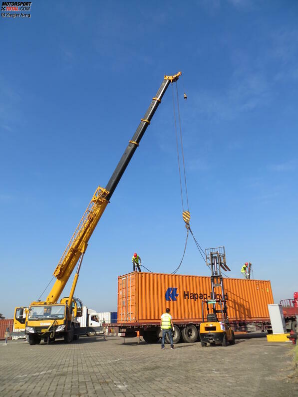 Zwei Arbeiter des lokalen Spediteurs werden mit einem Gabelstapler aufs Containerdach gehievt, um die schweren Trageketten anzuheften, dann hievt der Kran den Container auf seinen Platz. Dieses Schauspiel wiederholt sich an diesem Vormittag 35 Mal.