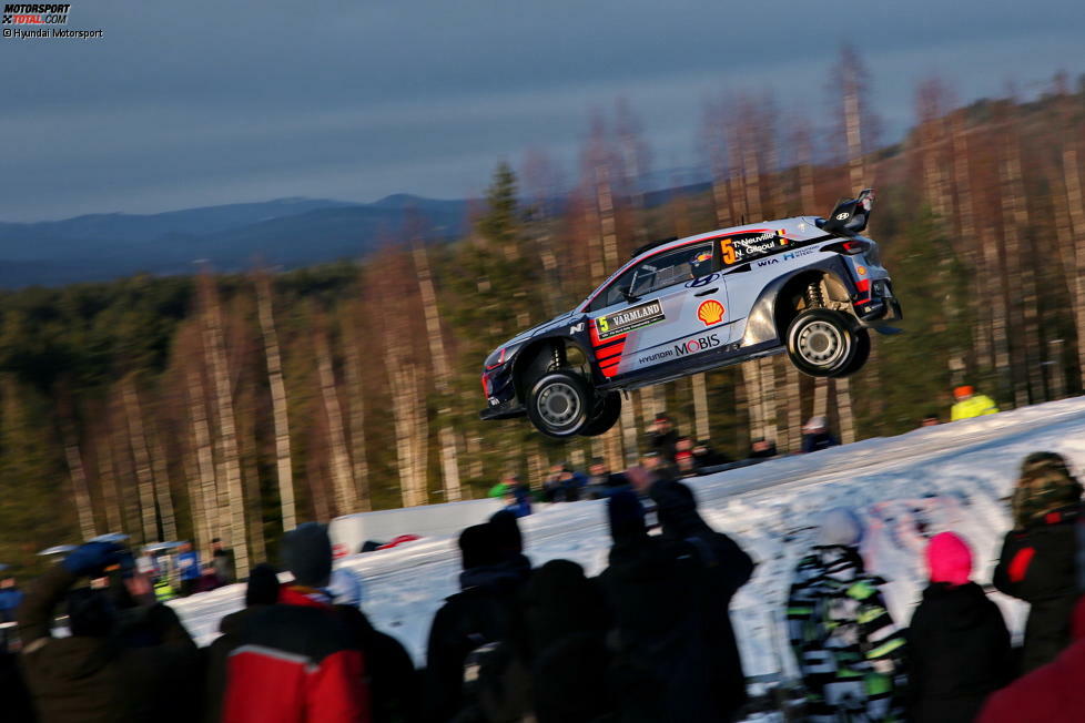 Die WRC-Boliden heben an der Kuppe ab und fliegen an den Köpfen der begeisterten Zuschauer vorbei.