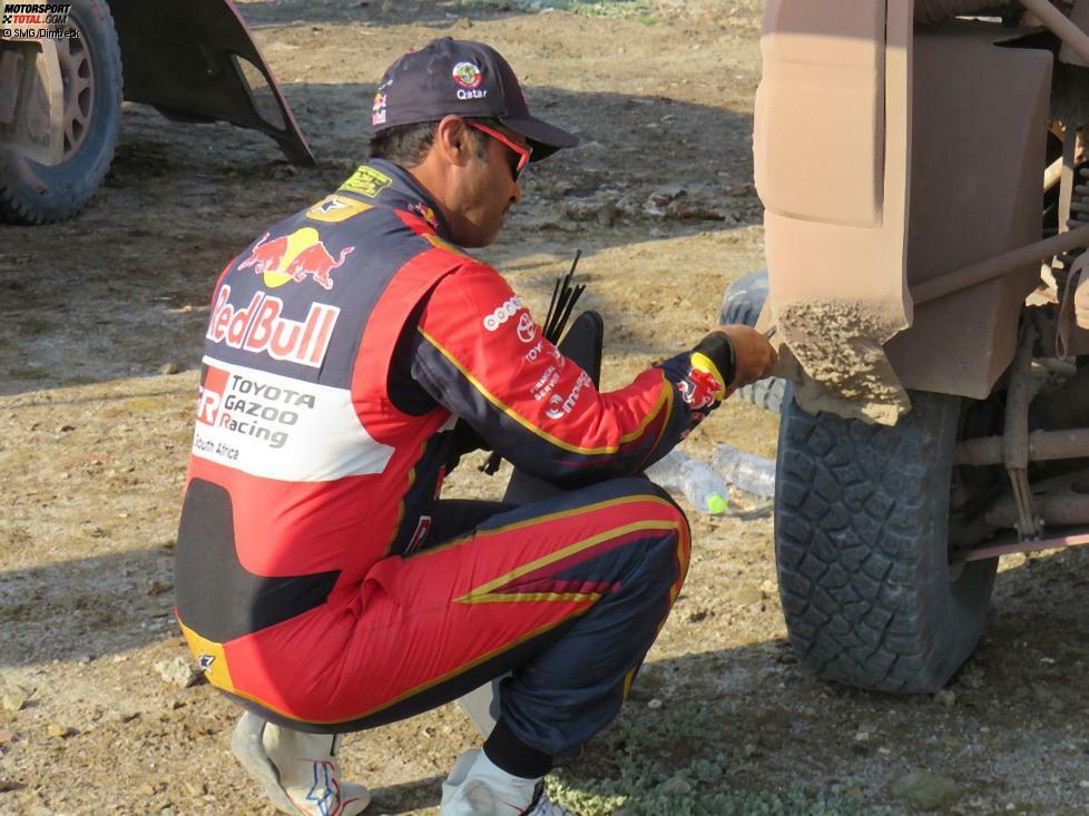 Nasser Al-Attiyah kratzt den mittlerweile getrockneten Dreck von seinem Hilux...