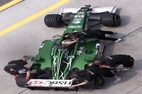Eddie Irvine wird von den Mechanikern in die Garage geschoben