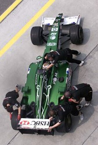 Titel-Bild zur News: Eddie Irvine wird von den Mechanikern in die Garage geschoben