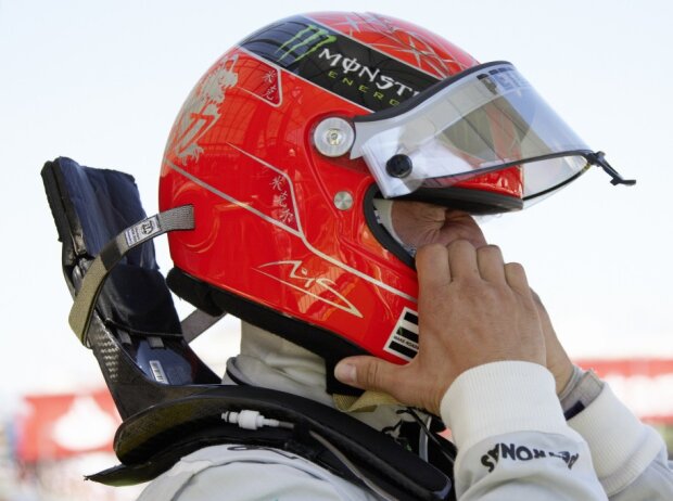 Titel-Bild zur News: Mercedes-Fahrer Michael Schumacher zieht sich in der Formel 1 seinen Helm mit HANS-System über