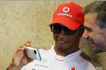 Lewis Hamilton (McLaren) zeigt Pressesprecher Steve Cooper seine neuesten Handyfotos