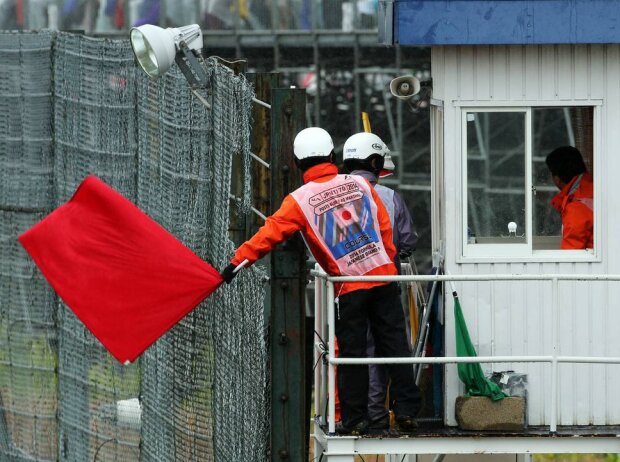 Titel-Bild zur News: Streckenposten zeigen in Suzuka die rote Flagge