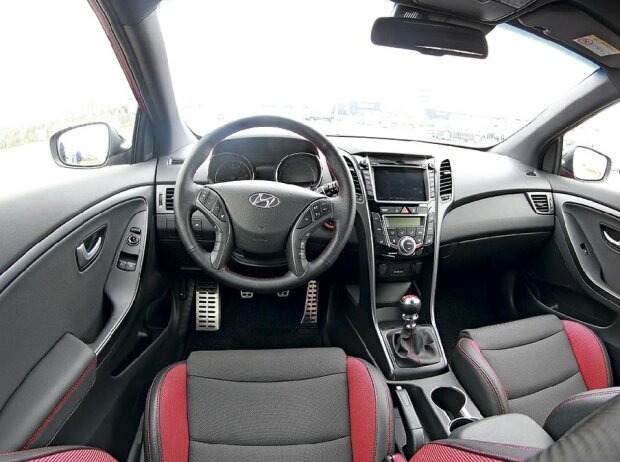 Cockpit des Hyundai i30 Turbo Serienmodells: Perforiertes Sportlenkrad, Alu-Pedalerie, Stoff-Leder-Sportsitze und ein roter Schaltknauf sind die Turbo-Merkmale des i30