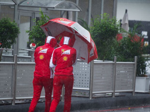 Titel-Bild zur News: Ferrari-Personal mit Regenschirm