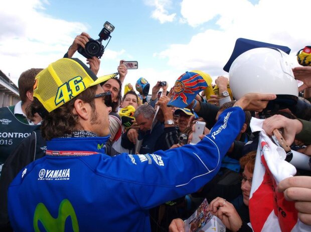 Titel-Bild zur News: Valentino Rossi schreibt Autogramme umringt von seinen Fans