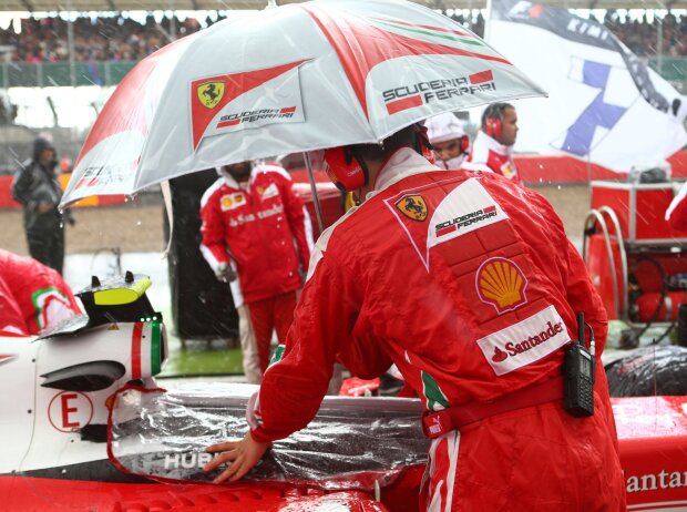 Titel-Bild zur News: Ferrari-Mechaniker mit Regenschirm
