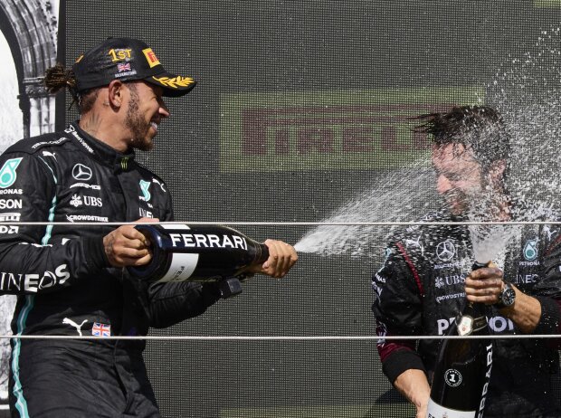 Formel 1 2021: Lewis Hamilton feiert seinen Sieg beim Grand Prix von Großbritannien 2021 in Silverstone mit Champagner der Marke Ferrari und einem Mercedes-Mitarbeiter