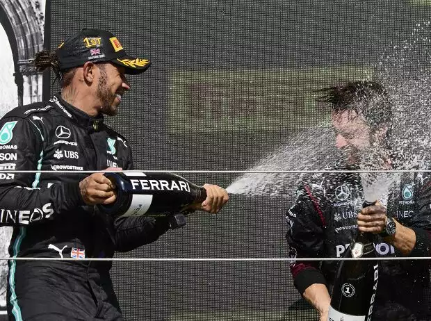Formel 1 2021: Lewis Hamilton feiert seinen Sieg beim Grand Prix von Großbritannien 2021 in Silverstone mit Champagner der Marke Ferrari und einem Mercedes-Mitarbeiter Titel-Bild zur News: Formel 1 2021: Lewis Hamilton feiert seinen Sieg beim Grand Prix von Großbritannien 2021 in Silverstone mit Champagner der Marke Ferrari und einem Mercedes-Mitarbeiter