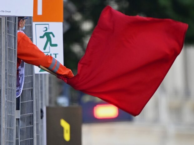 Ein Sportwart der Formel 1 schwenkt eine rote Flagge und signalisiert damit einen Abbruch der Einheit