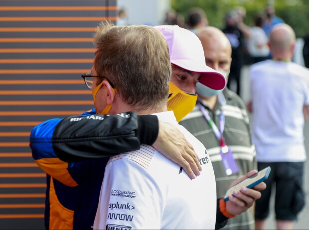 Daniel Ricciardo umarmt McLaren-Teamchef Andreas Seidl nach dem Sieg beim Grand Prix von Italien in Monza 2021 und schaut gleichzeitig auf sein Handy