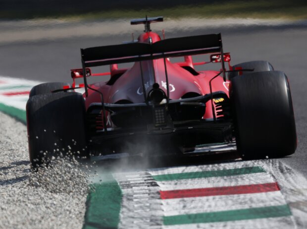 Titel-Bild zur News: Heckansicht von Charles Leclerc (Ferrari), der beim Durchfahren einer Kurve in Monza 2021 über den Randstein Kieselsteine aufwirbelt