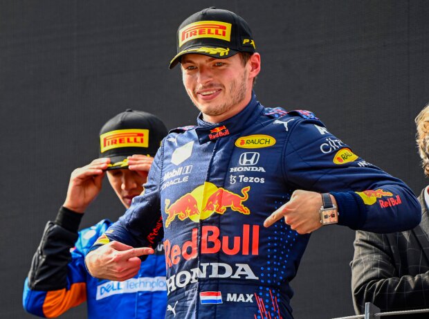 Titel-Bild zur News: Max Verstappen deutet auf das Red-Bull-Logo auf seinem Rennanzug