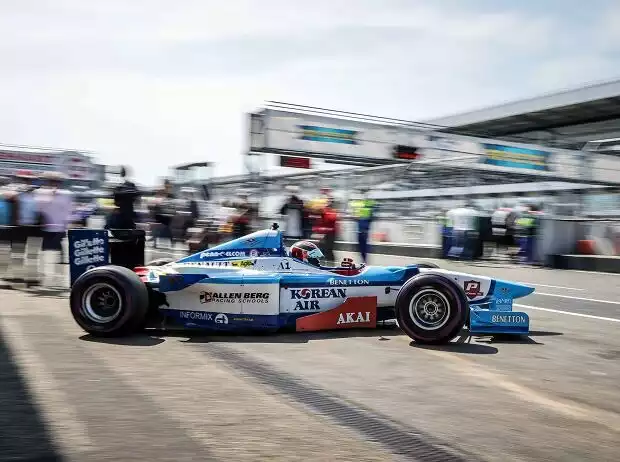 Ein blau-weißer Benetton Formel-1-Rennwagen ist von der Seite zu sehen, wie er seine Garage verlässt und in die Boxengasse einbiegt. Titel-Bild zur News: Ein blau-weißer Benetton Formel-1-Rennwagen ist von der Seite zu sehen, wie er seine Garage verlässt und in die Boxengasse einbiegt.