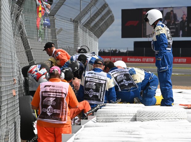 Helfer kümmern sich um den verunfallten Guanyu Zhou beim Formel-1-Rennen in Silverstone 2022 Helfer kümmern sich um den verunfallten Guanyu Zhou beim Formel-1-Rennen in Silverstone 2022