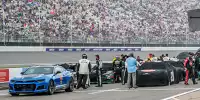 NASCAR-Autos unter Regenplanen in der Boxengasse des Michigan International Speedway