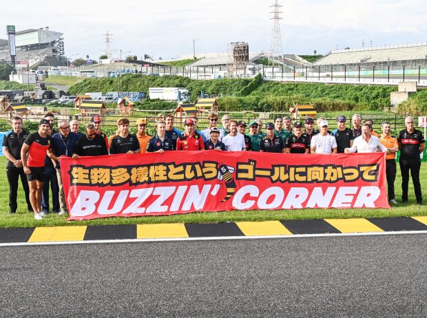 Sebastian Vettel mit den Formel-1-Fahrern hinter den gelb-schwarzen Randsteinen in Suzuka
