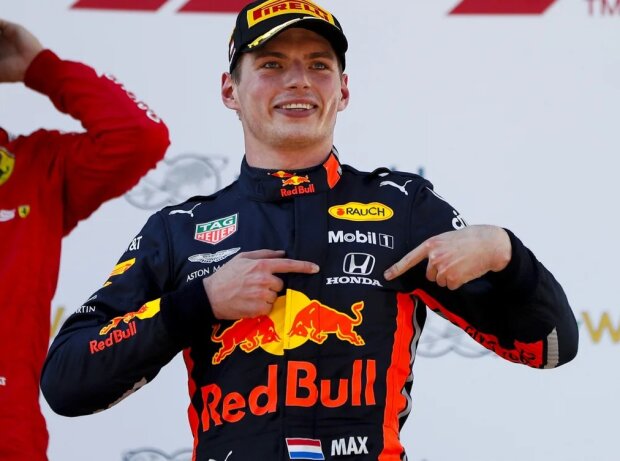 Titel-Bild zur News: Max Verstappen zeigt auf das Honda-Logo auf seinem Overall nach dem Sieg in Österreich 2019