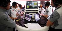 Blick in eine typische Formel-1-Garage: Ingenieure und Fahrer beim Sichten und Analysieren der Daten
