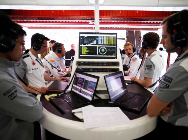 Titel-Bild zur News: Blick in eine typische Formel-1-Garage: Ingenieure und Fahrer beim Sichten und Analysieren der Daten