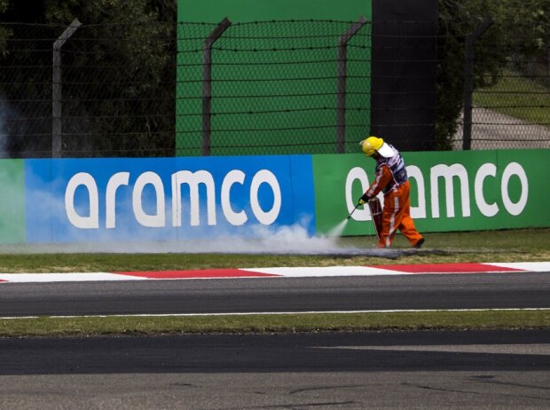 Ein Sportwart löscht den brennenden Rasen bei der Formel 1 in Schanghai 2024