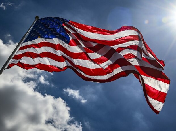 Titel-Bild zur News: Die US-amerikanische Flagge weht im Wind an der Rennstrecke