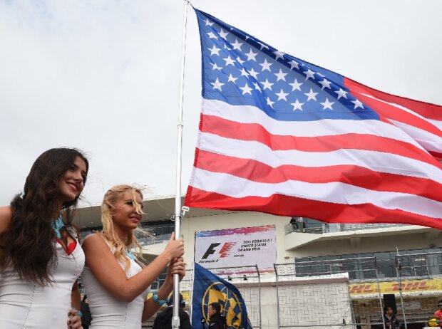 Titel-Bild zur News: Zwei Frauen posieren mit der US-Flagge in der Formel-1-Startaufstellung