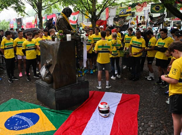 Titel-Bild zur News: Diesmal keine Bienen: Sebastian Vettel versammelt die Fahrer um Sennas Statue